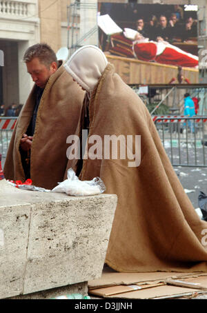 (Dpa) - due credenti, coperto di coperte, inginocchiati sul suolo e pregare davanti a una colonna di Piazza San Pietro durante le prime ore del mattino a Roma, Italia, 06 aprile 2005. La Basilica di San Pietro rimarrà aperta fino a venerdì 08 aprile 2005 per persone in lutto, pellegrini e visitatori provenienti da tutto il mondo che vogliono pagare il loro ultimo omaggio a Papa Giovanni Paolo II prima è prevista per il resto. Foto Stock