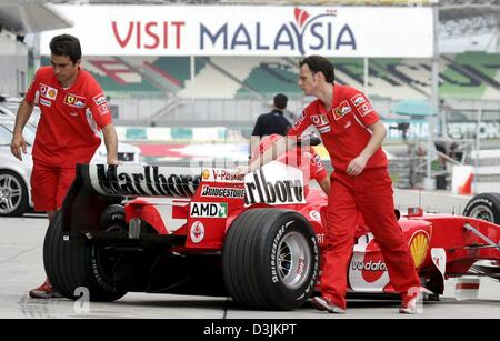 (Dpa) - meccanici Ferrari spingere indietro la vettura da corsa del tedesco pilota di Formula Uno Michael Schumacher nel box presso il Gran Premio della Malesia circuito, 16 marzo 2005 a Sepang vicino a Kuala Lumpur, Malesia. Il Gran Premio della Malesia ha luogo domenica 20 marzo 2005. Foto Stock