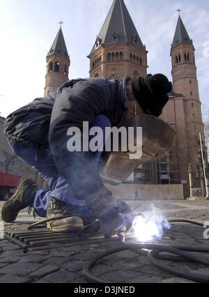 (Dpa) - Un lavoratore saldature chiuse un chiusino di fronte alla cattedrale e a Mainz, Germania, 21 febbraio 2005. Il presidente americano George Bush si visita la capitale dello stato tedesco della Renania Palatinato mercoledì 23 febbraio 2005. Il suo incontro con il cancelliere tedesco Gerhard Schroeder più tardi nella giornata si svolgerà sotto la sorveglianza di sicurezza. Foto Stock