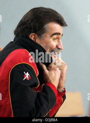 (Dpa) - team nazionale tedesco head coach Heiner Brand sorrisi e si ripiega il suo collare come egli guarda il suo team di turno preliminare gruppo D partita contro la Norvegia a uomini della squadra di pallamano Campionati del Mondo a Sousse, Tunisia, 27 gennaio 2005. La sala in cui il gioco è stato giocato è ormai soprannominato 'ice hall' dovuta al suo stato non riscaldata e tempo di gioco temperature di soli 8¡ Celciu Foto Stock