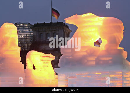 (Dpa) - illuminato sculture di ghiaccio che sono parte dell'ice bar che è stato eretto per il Capodanno del partito può essere visto di fronte al Reichstag mentre una bandiera tedesca le onde a mezz' asta per le vittime dello tsunami in Asia del sud di Berlino, Germania, 30 dicembre 2004. Circa un milione di visitatori sono attesi per il più grande della Germania Capodanno del partito. Foto Stock