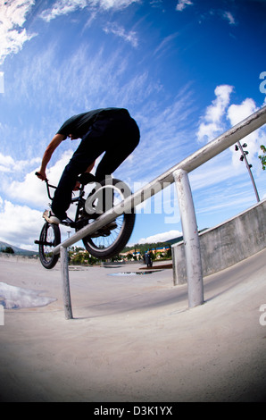 Biker facendo doppio peg smerigliare il corrimano su per le scale Foto Stock