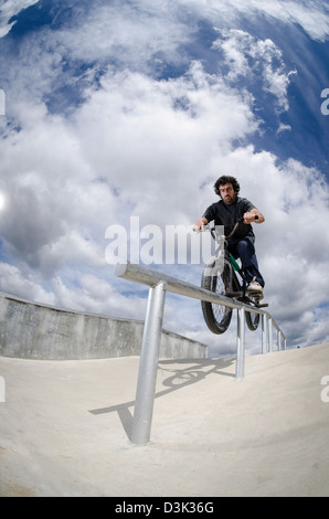 Biker facendo doppio peg smerigliare il corrimano su per le scale Foto Stock