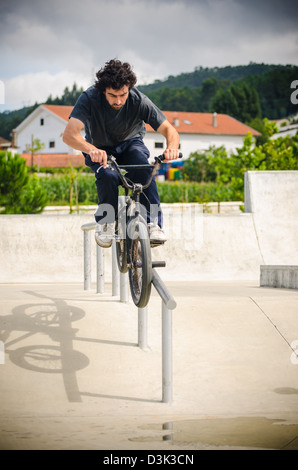 Biker facendo doppio peg smerigliare il corrimano su per le scale Foto Stock