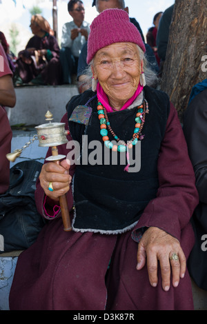 Anziani pellegrino femmina tenendo una ruota di preghiera e indossa una collana di turchese in un festival a Soma Gompa, Leh, (Ladakh) Jammu e Kashmir India Foto Stock