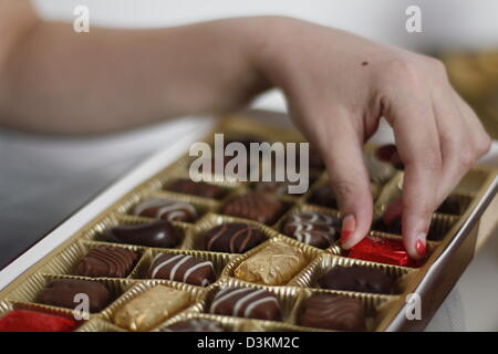 Mani di una giovane donna di prelevare i cioccolatini da una scatola a Bucarest, in Romania. Foto Stock