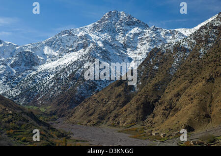 Le abitazioni lungo il sassoso River Valley, con montagne innevate dietro, armati village, vicino a Imlil, Marocco Foto Stock