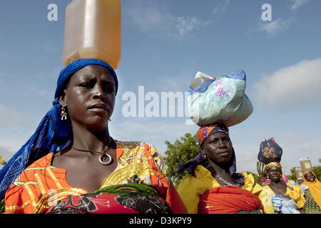 (Dpa) - Le donne portano il cibo, che hanno ricevuto all'alimentazione terapeutica centro dell'organizzazione umanitaria "edecins sans frontieres" (Medici senza frontiere) a Maradi, in Niger, 15 agosto 2005. La fame è un problema perenne in Niger e Mali, Mauritania e Burkina Faso ed è stata aggravata da una invasione di locuste lo scorso anno seguita da siccità. L'U.N. dice milioni ora faccia s Foto Stock
