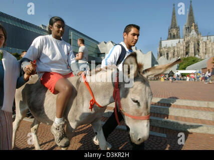 (Dpa) - Un pellegrino cavalcando un asino passa la cattedrale di Colonia, Germania, giovedì 18 agosto 2005. Oggi nel pomeriggio il Papa Benedetto XVI è atteso a Colonia per la cattolica XX Giornata Mondiale della Gioventù ha avuto origine dal suo predecessore Papa Giovanni Paolo II. Foto: Kay Nietfeld Foto Stock