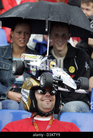 (Dpa) - due spettatori riparo dalla pioggia sotto un ombrello, mentre un altro ventilatore visualizza un gigante racing modello di auto su un casco durante la seconda sessione di prove sul circuito di Formula Uno di Francorchamps, Belgio, Venerdì 09 settembre 2005. Il Gran Premio del Belgio avrà luogo a Spa Francorchamps domenica 11 settembre. Foto: Gero Breloer Foto Stock