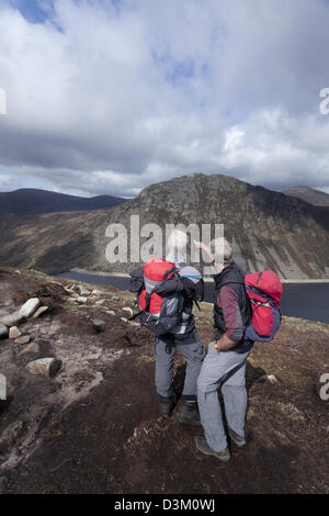 Due camminatori attraverso Ben Crom serbatoio dalle piste di Slieve Lamagan. Mourne Mountains, County Down, Irlanda del Nord. Foto Stock