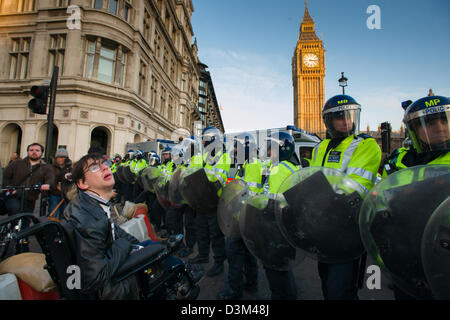 Uomo disabili in sedia a rotelle di fronte una linea di polizia in piena sommossa ingranaggio nella parte anteriore del case del Parlamento, giorno X3 manifestazione studentesca, Londra, Inghilterra Foto Stock