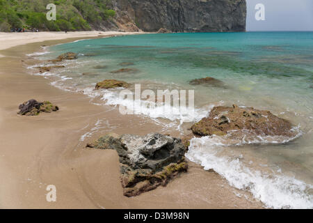 Onde che si infrangono su rocce di origine vulcanica sulla spiaggia sabbiosa a Rendezvous Bay, Montserrat Foto Stock