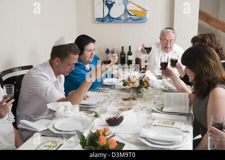 Famiglia seduti attorno a un tavolo per una festa ebraica pasto sulla Pasqua (traslitterato come Pesach o Pesah) Foto Stock