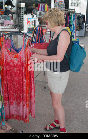 Donna matura guardando vestiti per la vendita su rack Meloneras, Maspalomas, Gran Canaria Foto Stock