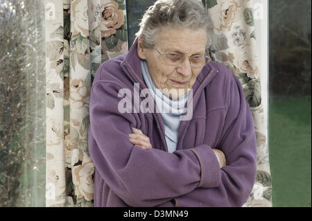 Donna anziana che indossa una giacca di lana e una calda sciarpa cercando di tenere in caldo in condizioni di basse temperature Foto Stock