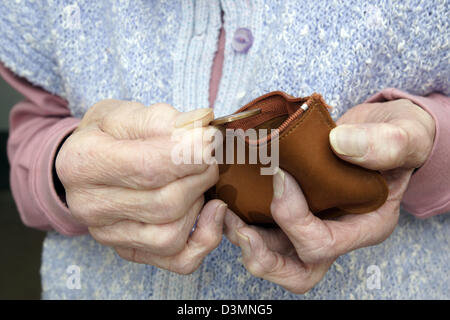 Donna anziana cercando nella sua borsa il conteggio del pennys in epoca di austerità e tempi preoccupanti Foto Stock