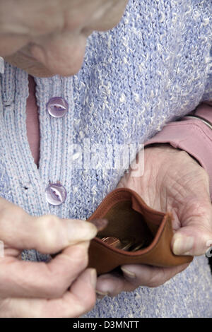 Donna anziana cercando nella sua borsa il conteggio del pennys in epoca di austerità e tempi preoccupanti Foto Stock