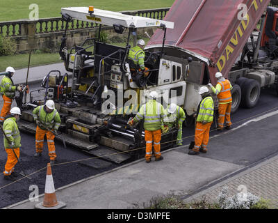 Una macchina pavior in azione la posa di asfalto dello strato di base su una strada di rettifica della superficie di lavoro Foto Stock