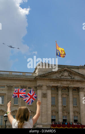 Battle of Britain Memorial Flight passando oltre Buckingham Palace di Londra - una giovane ragazza mostra il patriottismo - Queen orologi da balcone. Bandiere britanniche Foto Stock