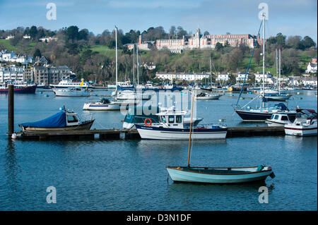 Grazioso e piccolo barche a vela punteggiato circa sul fiume Dart di fronte allo storico Britannia Royal Naval School (BRNC) Foto Stock