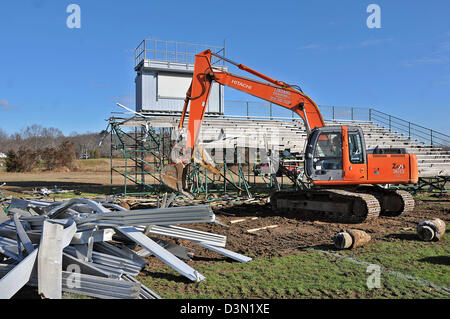 Un wrecker abbatte le gradinate in uno stadio di calcio in Madison CT USA come la città si prepara a costruire una nuova. Foto Stock