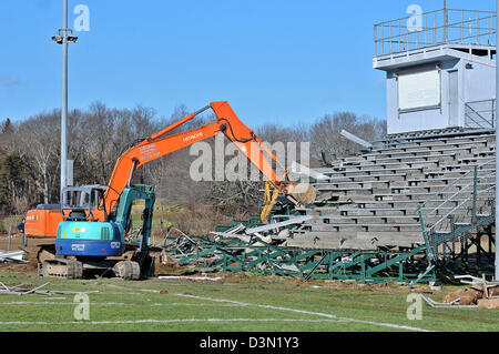 Un wrecker abbatte le gradinate in uno stadio di calcio in Madison CT USA come la città si prepara a costruire una nuova. Foto Stock