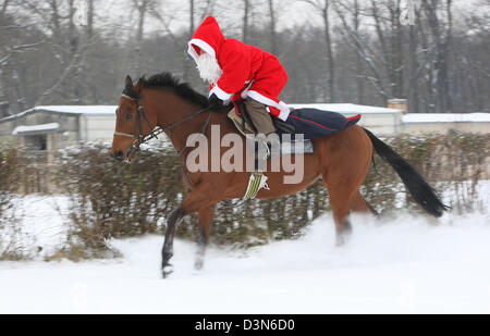 Hoppegarten, Germania, Santa Claus in sella a un cavallo attraverso la neve Foto Stock