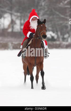 Hoppegarten, Germania, Santa Claus in sella a un cavallo attraverso la neve Foto Stock