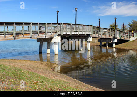 Un piccolo ponte pedonale che attraversa un laghetto in un parco in una giornata di sole. Foto Stock