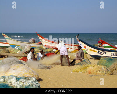 (Dpa) file - pescatori riparare le reti mentre è seduto dietro colorfully dipinto barche da pesca su una spiaggia presso la costa del Coromandel vicino a Mahabalipuram (Mamallapuram) nello stato di Tamil Nadu, India, 25 febbraio 2006. La maggior parte delle barche sono state finanziate da diversi donatori di aiuti dopo la tsumami aveva colpito la costa in dicembre 2004 e ha provocato numerose vittime nonché danni estesi al Foto Stock