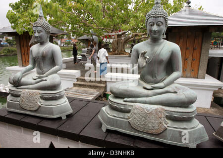 I turisti riguardo la bella premessa del tempio di Gangaramaya in Colombo, Sri Lanka, 24 aprile 2006. In primo piano si trovano due statue del Buddha in meditazione. Il Gangaramaya tempio è uno dei più bei templi buddhistic nella capitale dello Sri Lanka. Foto: Maurizio Gambarini Foto Stock