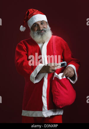 Uomo vestito da Santa Claus in possesso di un telefono cellulare Foto Stock