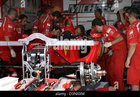 I meccanici della scuderia Ferrari del team lavorano su Michael Schumacher la vettura dopo il suo motore ha preso fuoco in pit lane durante la terza sessione di prove libere a gara di Magny Cours via vicino a Nevers, Francia, Sabato, 15 luglio 2006. Il Gran Premio di Francia si terrà il 16 luglio 2006. Foto: Rainer Jensen Foto Stock