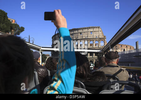 I turisti su di un autobus aperto sul tetto tour di Roma prendendo fotografie del Colosseo anfiteatro Foto Stock