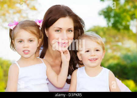 Foto di bella donna con due bambini carino, closeup Ritratto di giovane madre con dolce figlia e adorabile figlio all'aperto Foto Stock