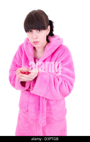 La giovane donna in una vestaglia detiene una manciata di compresse Foto Stock