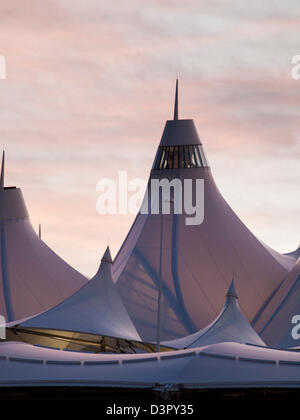 Incandescente tende di dia a sunrise. L'aeroporto internazionale di Denver ben noto per tetto a falde. design del tetto è riflettente montagne innevate. Foto Stock