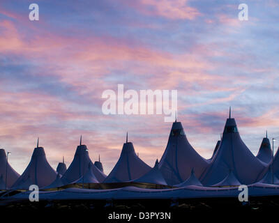 Incandescente tende di dia a sunrise. L'aeroporto internazionale di Denver ben noto per tetto a falde. design del tetto è riflettente montagne innevate. Foto Stock