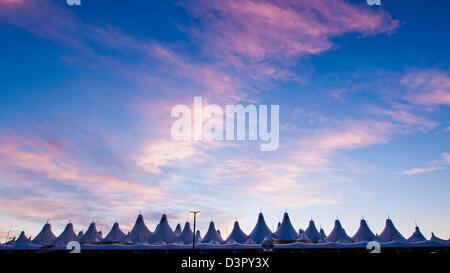 Incandescente tende di dia a sunrise. L'aeroporto internazionale di Denver ben noto per tetto a falde. design del tetto è riflettente montagne innevate. Foto Stock