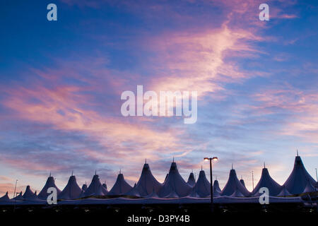 Incandescente tende di dia a sunrise. L'aeroporto internazionale di Denver ben noto per tetto a falde. design del tetto è riflettente montagne innevate. Foto Stock