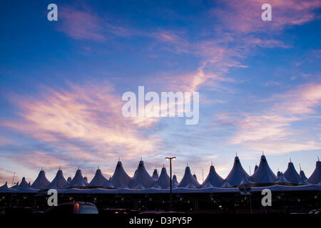 Incandescente tende di dia a sunrise. L'aeroporto internazionale di Denver ben noto per tetto a falde. design del tetto è riflettente montagne innevate. Foto Stock