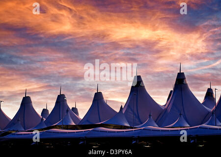 Incandescente tende di dia a sunrise. L'aeroporto internazionale di Denver ben noto per tetto a falde. design del tetto è riflettente montagne innevate. Foto Stock