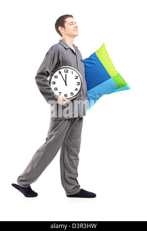 A piena lunghezza Ritratto di una giovane con cuscino e orologio sonnambulismo isolati su sfondo bianco Foto Stock