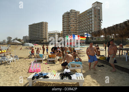 Famagusta, Repubblica Turca di Cipro del Nord, i turisti sulla spiaggia, in background fatiscenti alberghi Foto Stock