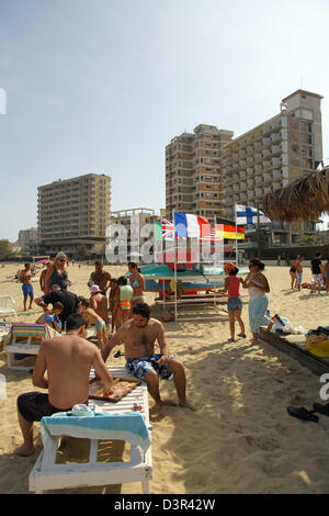 Famagusta, Repubblica Turca di Cipro del Nord, i turisti sulla spiaggia, in background fatiscenti alberghi Foto Stock