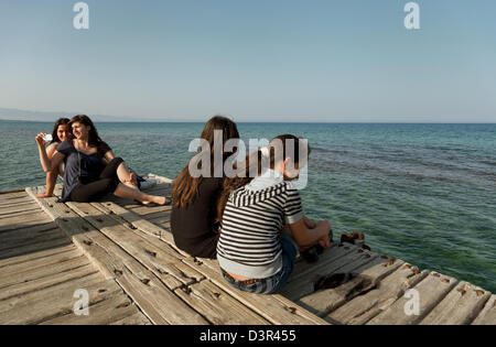 Famagusta, Repubblica Turca di Cipro del Nord, ragazza seduta su un dock nel Mediterraneo Foto Stock