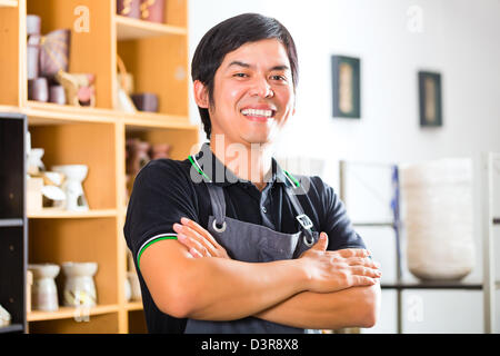 Asian venditore o potter in ceramica, egli mostra con orgoglio il suo lavoro Foto Stock