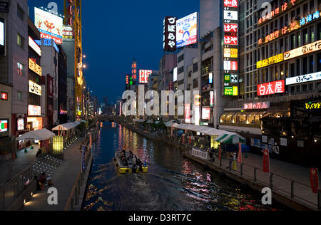 In barca per visite guidate si muove lentamente passato insegne al neon lungo Dotonbori-gawa (fiume Dotonbori) in Namba quartiere dei divertimenti di Osaka. Foto Stock