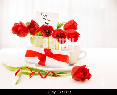 Foto di di bella tulipani pentola con cartoline di auguri, confezione regalo e una tazza di caffè sul tavolo a casa, stagione primaverile, Foto Stock